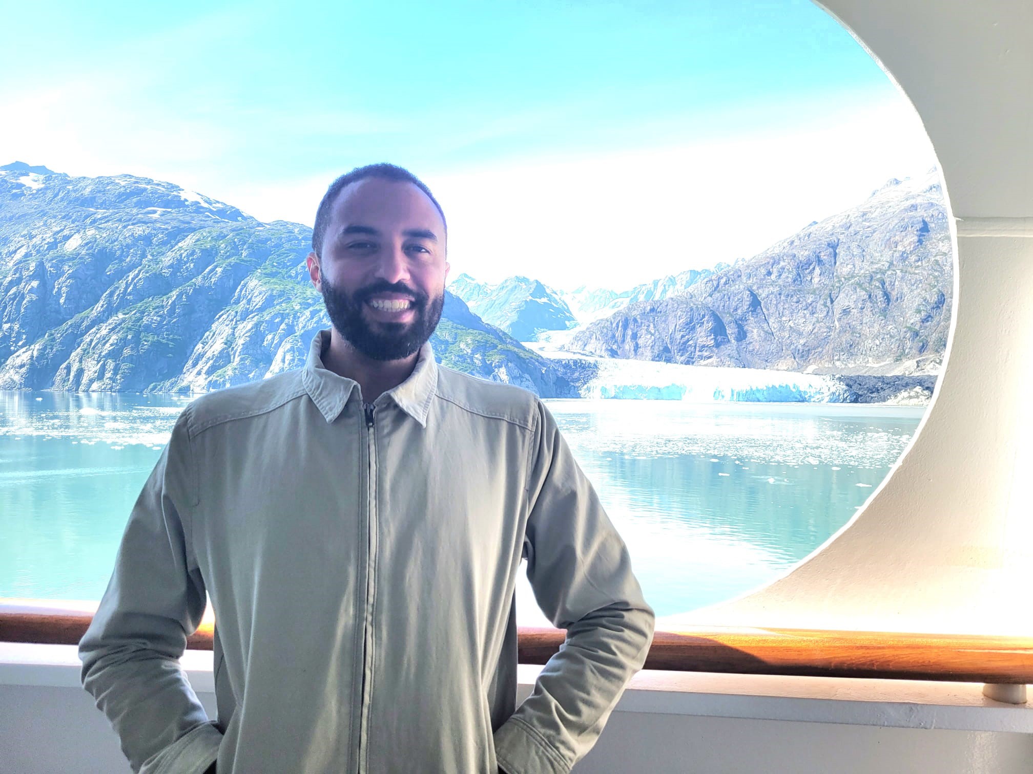 A photo of Dr. Hannibal Person smiling in front of a view of mountains and water.