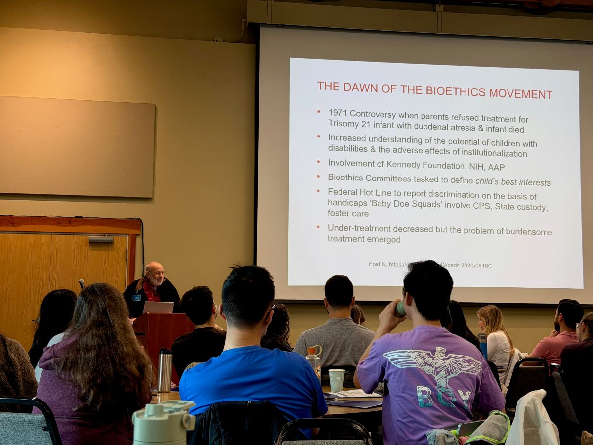 An audience views a slide presentation. 