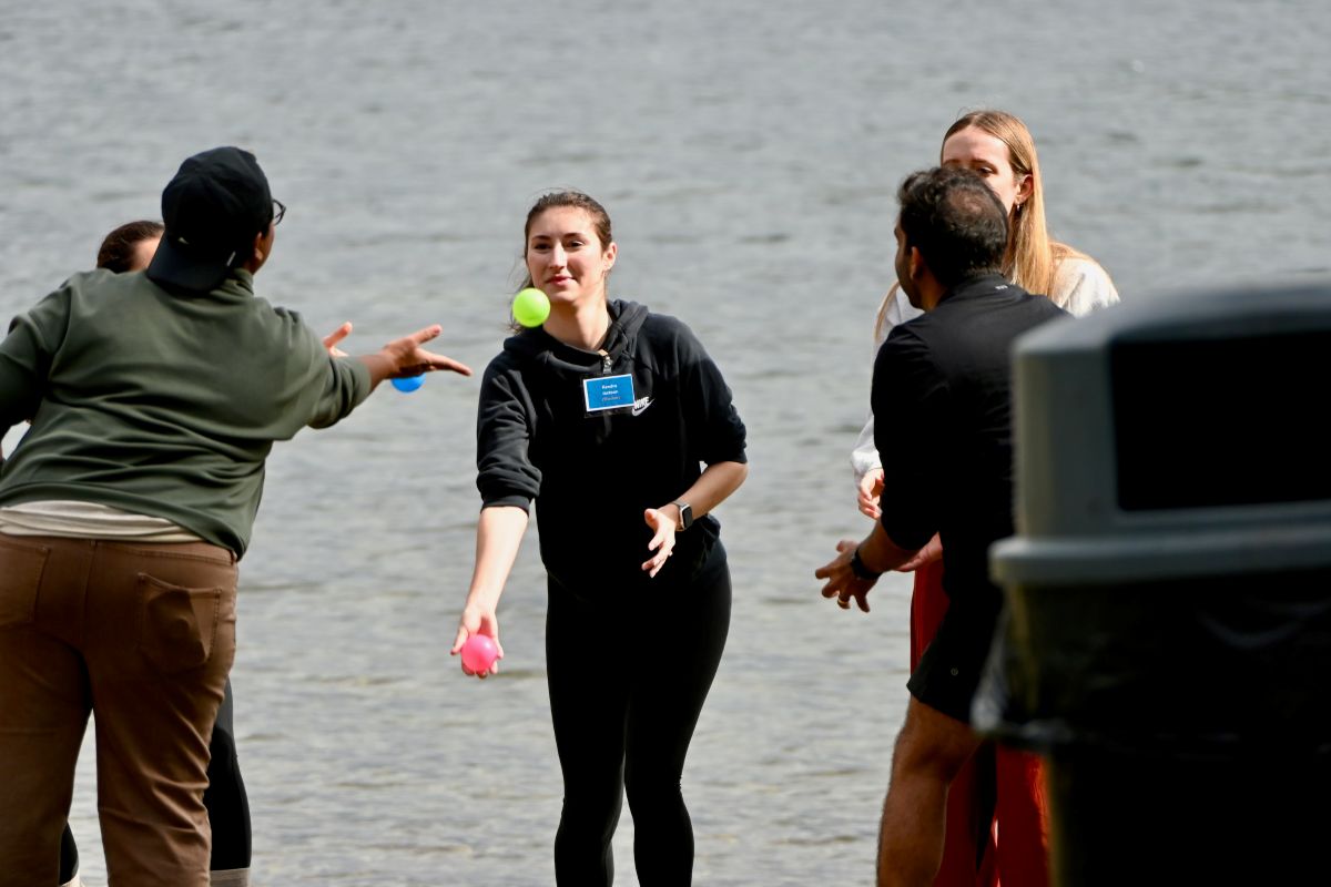 People toss a ball back and forth with water in the background.